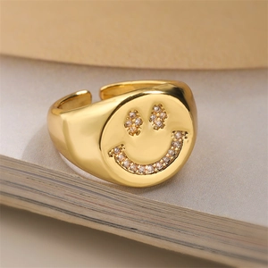 Close-up of a gold smiling face ring with inlaid zircons on a vintage book background
