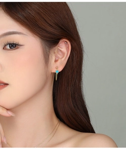 Detail of s925 silver turquoise earrings with gold tassels on a model