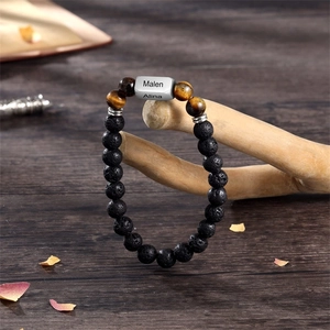 Detail of beaded men bracelet with lava stone, tiger eye and personalized engraved bead