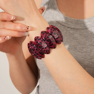 Détail du bracelet en résine léopard rose rouge au poignet avec finition brillante et large