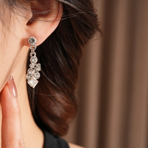 Detailed view of silver diamond geometric earrings worn by model with sparkling crystals