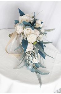 Close-up of cascading bridal bouquet with white roses, blue berries and lace ribbon
