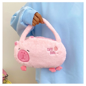 Detail of pink plush Capybara handbag with embroidered lettering held by a model
