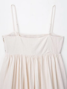 Detailed shot of cream embroidery dress straps with adjustable buckles and pleated fabric