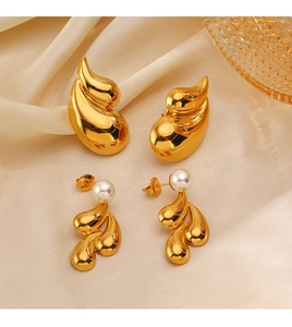Detail of 18K gold plated teardrop earrings and pearl studs on beige silk fabric