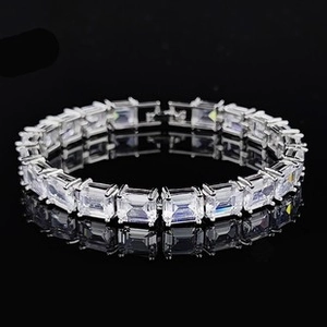 Macro view of silver tennis bracelet with emerald-cut white crystals on black surface