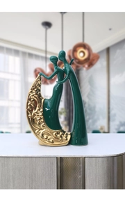 Close-up of ceramic abstract figure sculpture in dark green with gold floral patterns