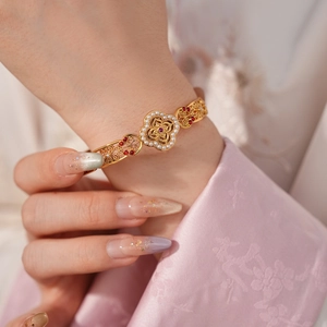 Detail of vintage gold brushed cuff bracelet with floral motif and red gemstones on wrist