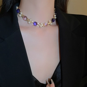 Détail d'un collier vintage doré avec pierres violettes et roses et perles