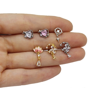 Detailed macro view of gold heart and lotus stud earrings set with pink zirconia stones