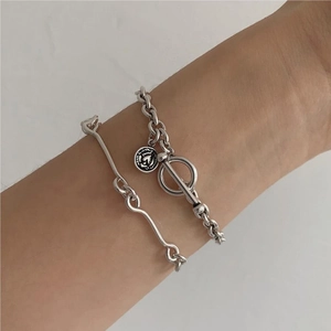 Detail of vintage silver chain bracelet with coin pendant and wavy line minimalist bangle