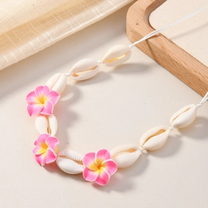 Détail d'un collier en coquillage avec des fleurs de frangipanier sur plateau