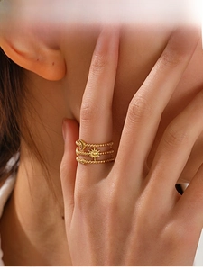 Detail view of triple-layered gold stainless steel ring with moon, sun and star charms