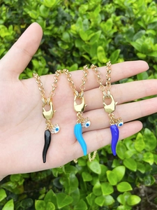 Detailed view of evil eye cornicello chili pendants in black, light blue, and dark blue