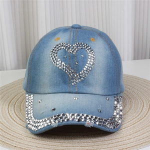 Détail d'un cœur en strass étincelant et d'une visière cloutée sur une casquette en jean