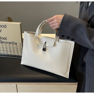 Detail of minimalist cream faux leather tote bag with envelope flap and button closure
