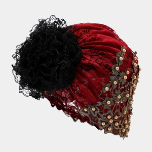 Détail macro du turban en dentelle rouge avec fleur 3D noire et broderie dorée