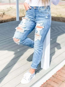 Détail du jean bleu avec texture en denim délavé et design déchiré au niveau du genou