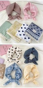 Detail of assorted cotton linen scarves with white lace trim in floral and plaid patterns