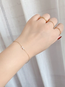 Detail of S925 sterling silver gold bow bracelet and textured rings on model's hand