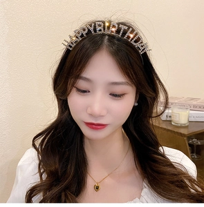 Detail of gold Happy Birthday headband with rhinestones worn by a model in a cozy setting