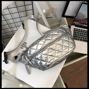 Detailed close-up of metallic silver quilted waist bag with woven zipper pull and woven strap