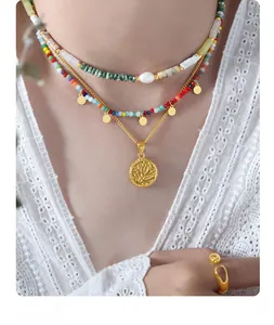 Detail of layered gold necklace with round embossed pendant, pearls and colorful beads