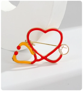 Macro view of heart-shaped stethoscope enamel brooch with red and gold alloy details