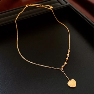 Dettaglio macro della collana placcata oro 18K con ciondolo a cuore spazzolato e perline