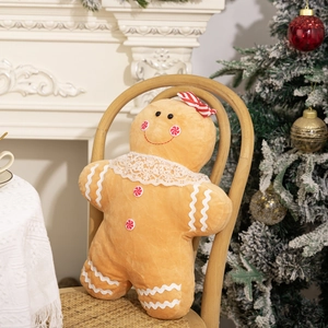 Gingerbread man plush pillow on a chair with Christmas tree and fireplace background