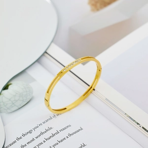 Detail shot of golden stainless steel bangle featuring seven inlaid clear zircon stones