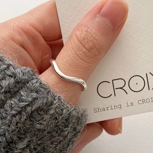 Minimalist 925 sterling silver wavy ring with high-polished finish worn on thumb