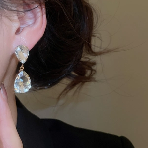 Close-up of elegant gold waterdrop tassel earrings with clear crystal stones on model