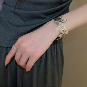 Dettaglio del set bracciale e anello a fiore in metallo vintage con texture rifinita