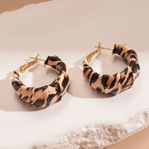 Detail of leopard print hoop earrings with leather texture and golden metal accents