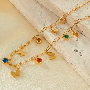Macro detail of gold butterfly necklace with colorful zircons on paperclip chain