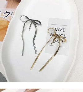 Detailed view of gold and silver metallic snake chain bow hairpins on a white ceramic plate