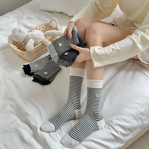 Detailed close-up of striped cotton socks with cute bear embroidery on white background