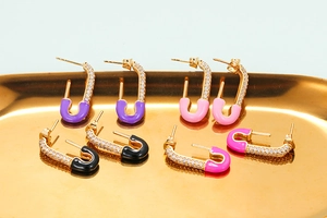 Golden paperclip earrings with colorful enamel and zircon crystals on a luxury tray