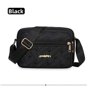 Close-up of quilted nylon crossbody bag with heart embroidery and gold brand logo