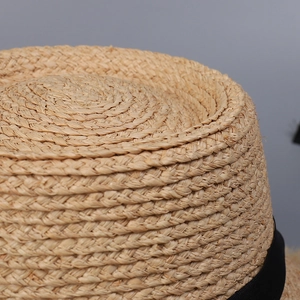 Detailansicht eines Raffia-Sonnenhuts mit schwarzem Band und Spiralwebstruktur