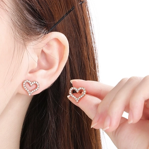 Close-up of heart-shaped rose gold stud earrings featuring micro-pave crystal settings