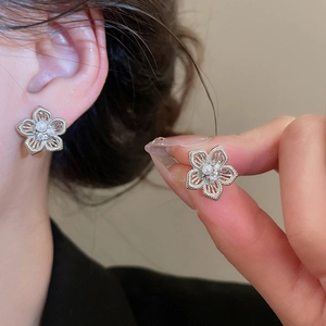 Nahaufnahme eleganter hohlförmiger Blumenohrringe mit Perle und funkelnden Strasssteinen