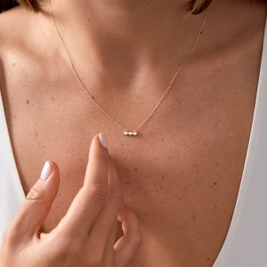 Gros plan détaillé d'un collier à trois pierres en zircon plaqué or 18 carats sur acier