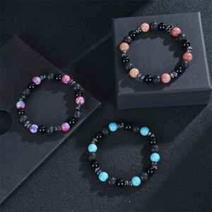 Macro detail of 8mm volcanic stone and colorful gemstone beaded bracelets on dark cubes