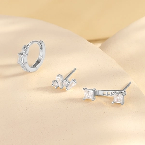 Detailed view of S925 sterling silver earring set with minimalist zircon studs on a beige surface