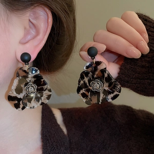Detail view of leopard print resin flower earrings with metal rose core on a model