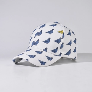 Close-up of baseball cap featuring blue pigeon prints and one yellow bird on white fabric