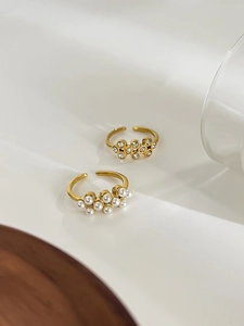 Detailed view of two 18k gold-plated rings featuring pearl and rhinestone honeycomb clusters