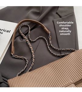 Detail of light brown striped embossed shoulder bag with metal chain strap on gray suit